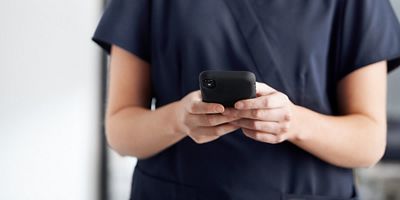 Close-up of nurse using mobile device in hospital hallway