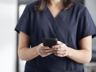 Close-up of nurse using mobile device in hospital hallway