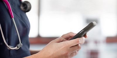 Close-up of nurse using mobile device in hospital hallway
