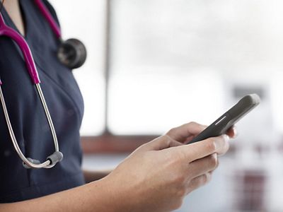 Close-up of nurse using mobile device in hospital hallway