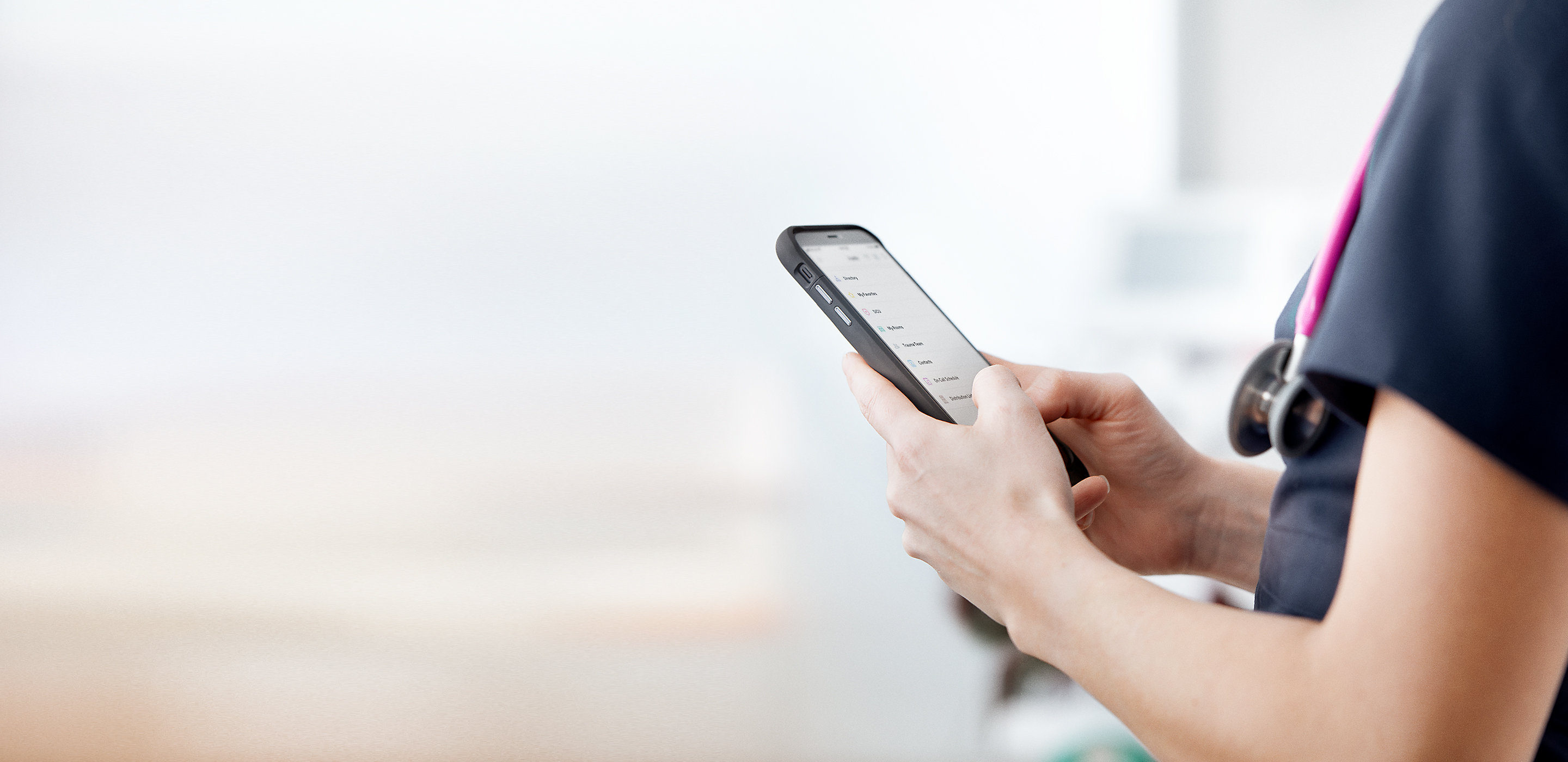 Una profesional de la salud lee un mensaje en su teléfono inteligente en la habitación de un paciente