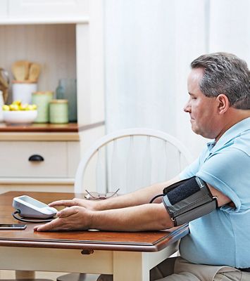 Man sitting at table using a blood pressure device