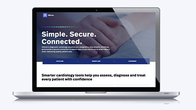 An open laptop computer displays the Hillrom diagnostic cardiology solutions website.