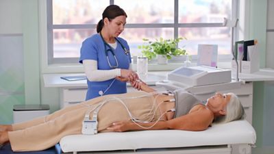 boy sitting in chair with nurse and vital signs monitor