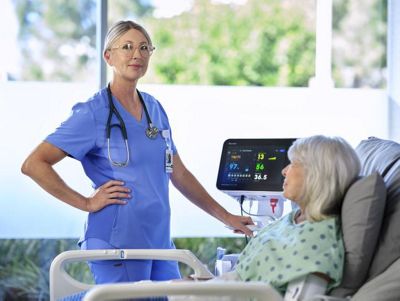 nurse with patient in hospital bed next to Connex 360™ monitor