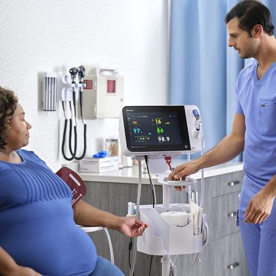 woman in chair sitting in exam room with Connex 360 Monitor and nurse