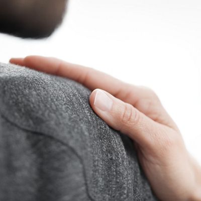 Close-up on a hand placed supportively on another’s shoulder