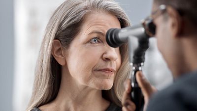 Physician looking at patients eye with panoptic ophthalmoscope 