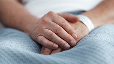 A close up of a patient's hands are shown with ID bracelet