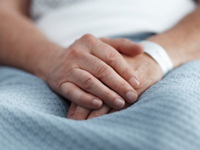 A close up of a patient's hands are shown with ID bracelet