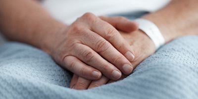 A close up of a patient's hands are shown with ID bracelet