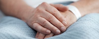 Hands folded on a patient’s lap in an acute care setting 
