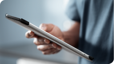 Hand holding a tablet device in a professional healthcare setting.