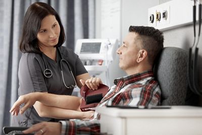 An urgent care clinician applies a blood pressure cuff to a patient's arm.