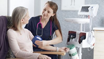 A nurse puts a blood pressure cuff on a patient’s arm to measure their blood pressure with the Connex Spot Monitor. 