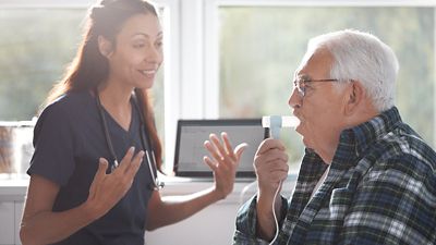 A patient blows into a spirometer connected to the Welch Allyn Diagnostic Cardiology Suite Spirometry. 