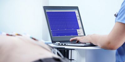 Clinician types on a laptop hosting the Welch Allyn Diagnostic Cardiology Suite ECG
