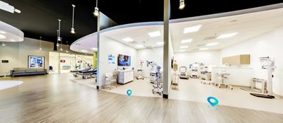 A patient smiles in a Centrella Smart+ Bed. Her clinician stands near the Graphical Caregiver Interface (GCI) Touchscreen.