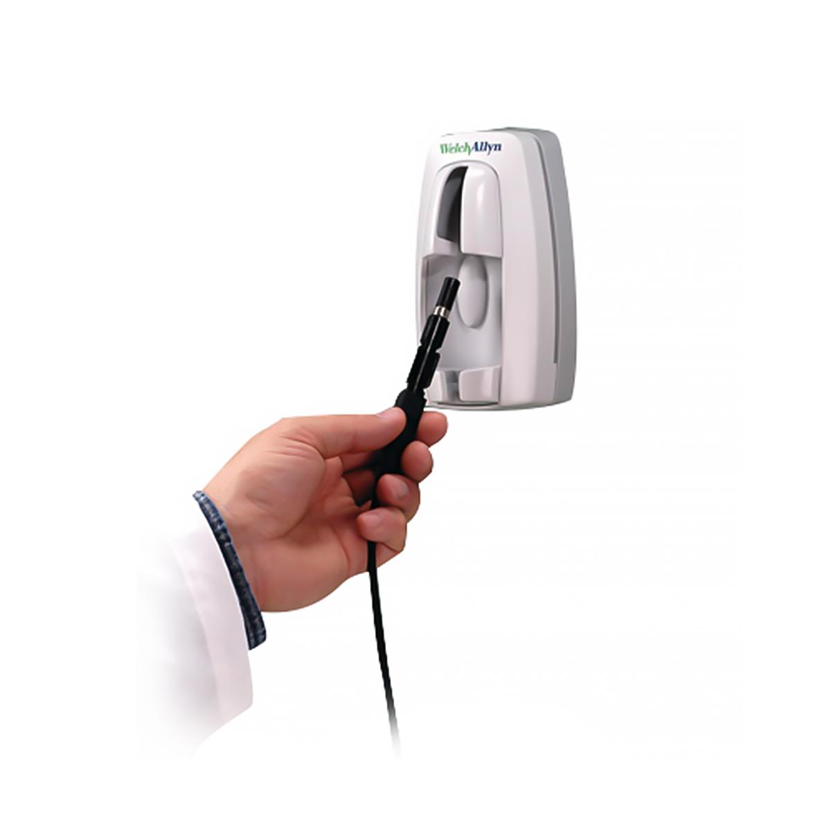 A clinician inserts the 78800 Series KleenSpec Corded Illumination System into its wall-mounted storage system