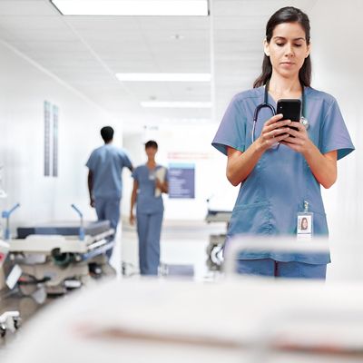 Nurse using smartphone in hospital hallway