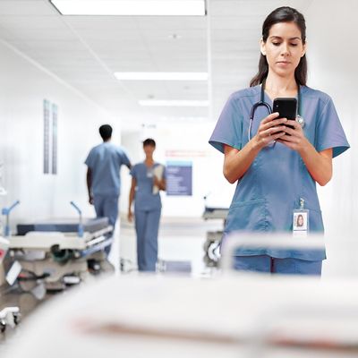 Infirmière qui utilise un téléphone intelligent dans un couloir d’hôpital