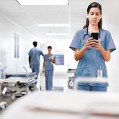 Eine Pflegekraft verwendet ein Smartphone auf dem Krankenhausflur
