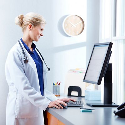 Physician smiles while reviewing patient data on a desktop computer monitor