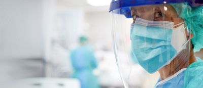 Close up view of a nurse or doctor wearing surgical mask and a face shield.