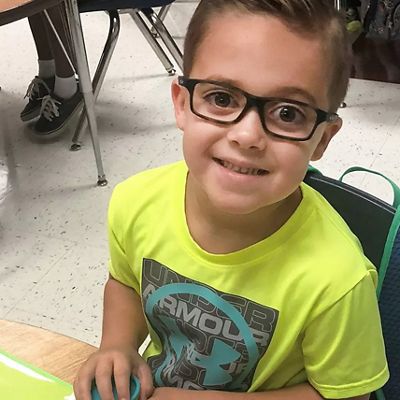 a child is shown smiling wearing glasses