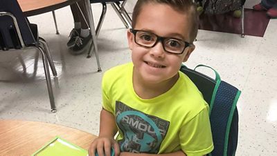 a child is shown smiling wearing glasses