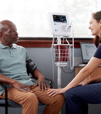 Female clinician talks to male patient after a blood pressure exam. 