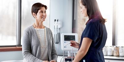 A clinician is about to take a patient’s temperature with an automated vital signs device.