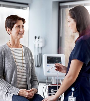 A clinician is about to take a patient’s temperature with an automated vital signs device.
