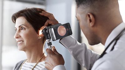 A doctor looks into a patient’s ear with the MacroView Plus Otoscope.