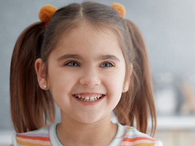 Child with pigtails smiles after getting vision screening.