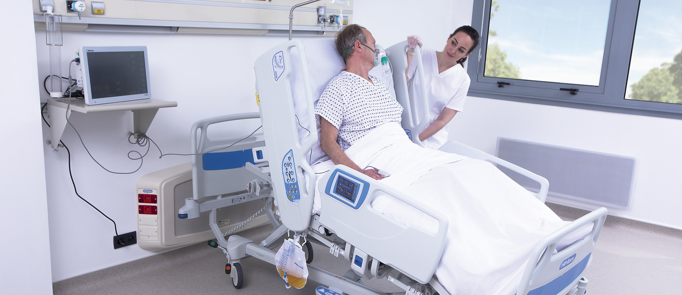 En läkare justerar en Hillrom 900 Accella smart säng för en patient