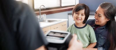 Un médico realiza un examen de la vista a un niño utilizando el Evaluador de visión Spot®.