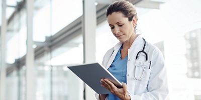 Primer plano del un médico usando el dispositivo para tableta en el pasillo del hospital