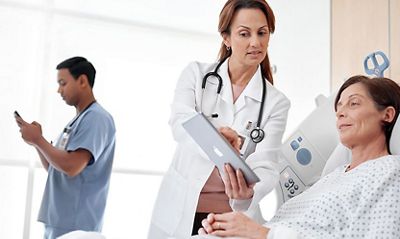 Nurse showing Voalte patient data on ipad to patient in Centrella Smart bed