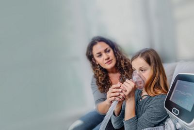 Mother helping young girl use the Volara System for airway clearance therapy