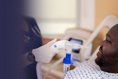 Man in hospital receiving airway clearance therapy with the Volara System